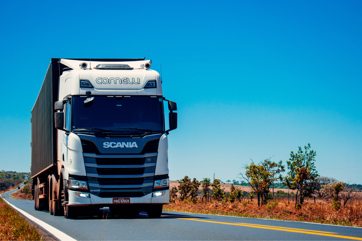 Camión de carga Scania de Fruitmove S.L. transitando por una carretera con cielo despejado de fondo, simbolizando la entrega confiable y eficiente de mercancías